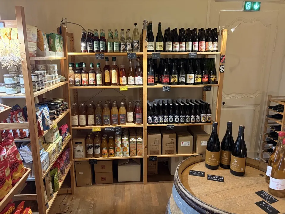 Étagères en bois avec des jus de fruits, des limonades et des bières, des chips et des bocaux à gauche, et un tonneau au premier plan.