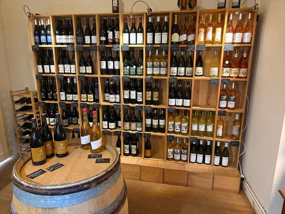 Mur de casiers en bois rempli de bouteilles de vin, avec un tonneau au premier plan.